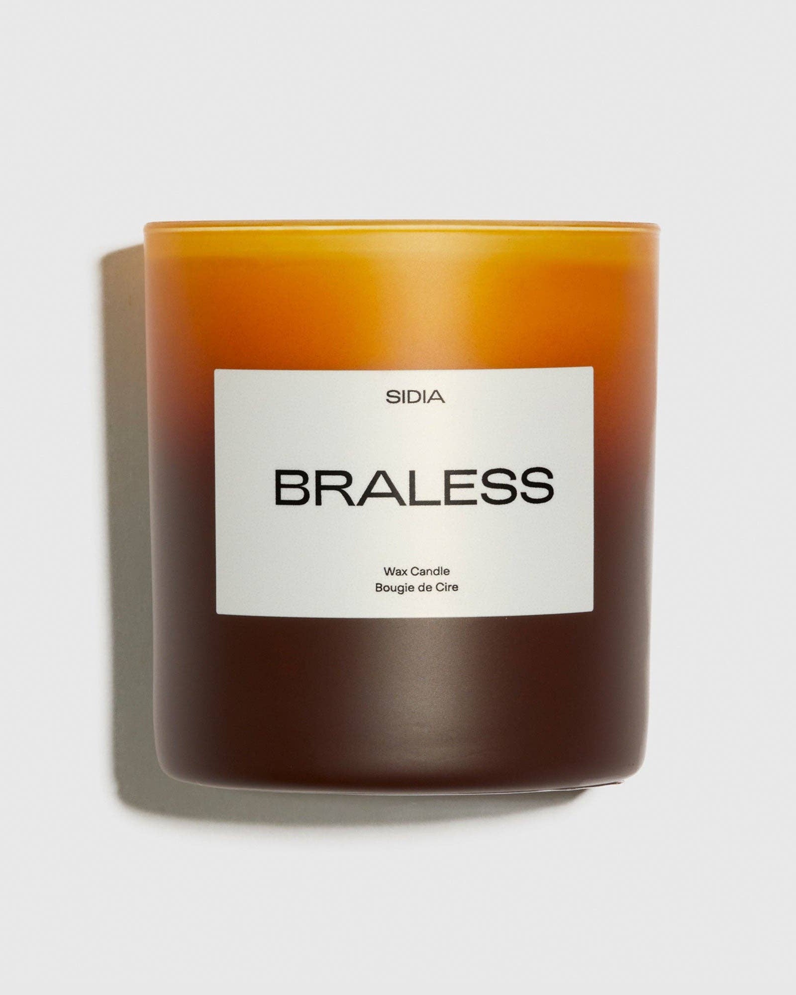 Candle with a label reading 'Braless' on a light gray background