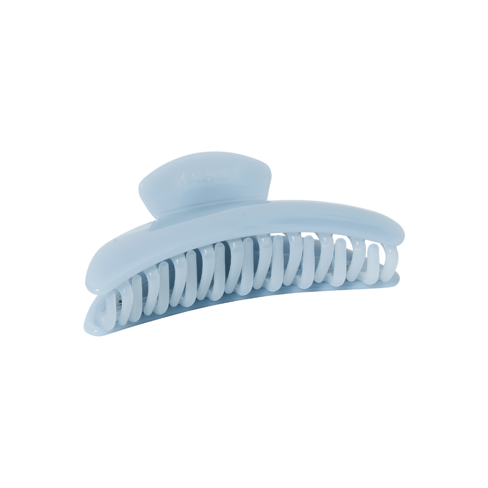 The Slim Hair Claw Clip — Mist by Karst Essentials is a sky blue cellulose acetate accessory with curved, interlocking teeth, displayed elegantly on a plain white background.