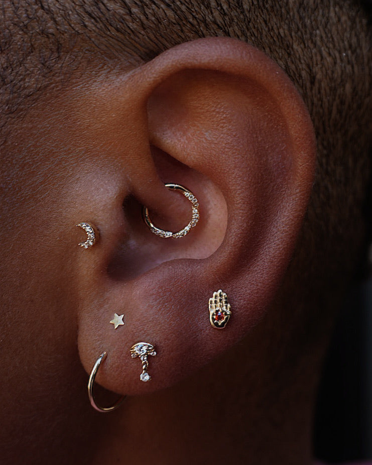 Close-up of an ear with multiple gold earrings on a dark background