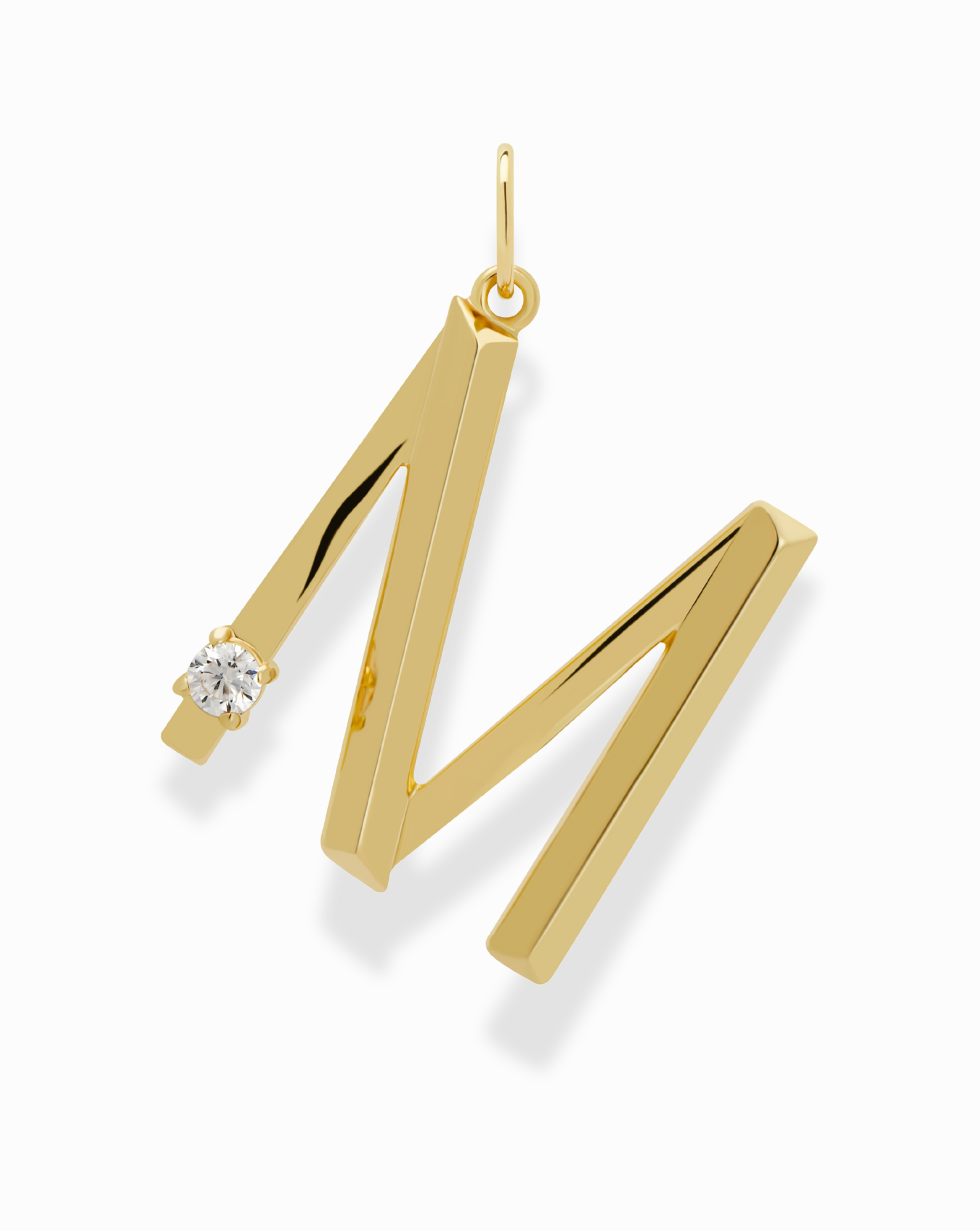 The Eloise Letter Charm by Mod + Jo is a gold pendant shaped like the letter M, accented with a sparkling cubic zirconia on the upper left side, shown against a white background.