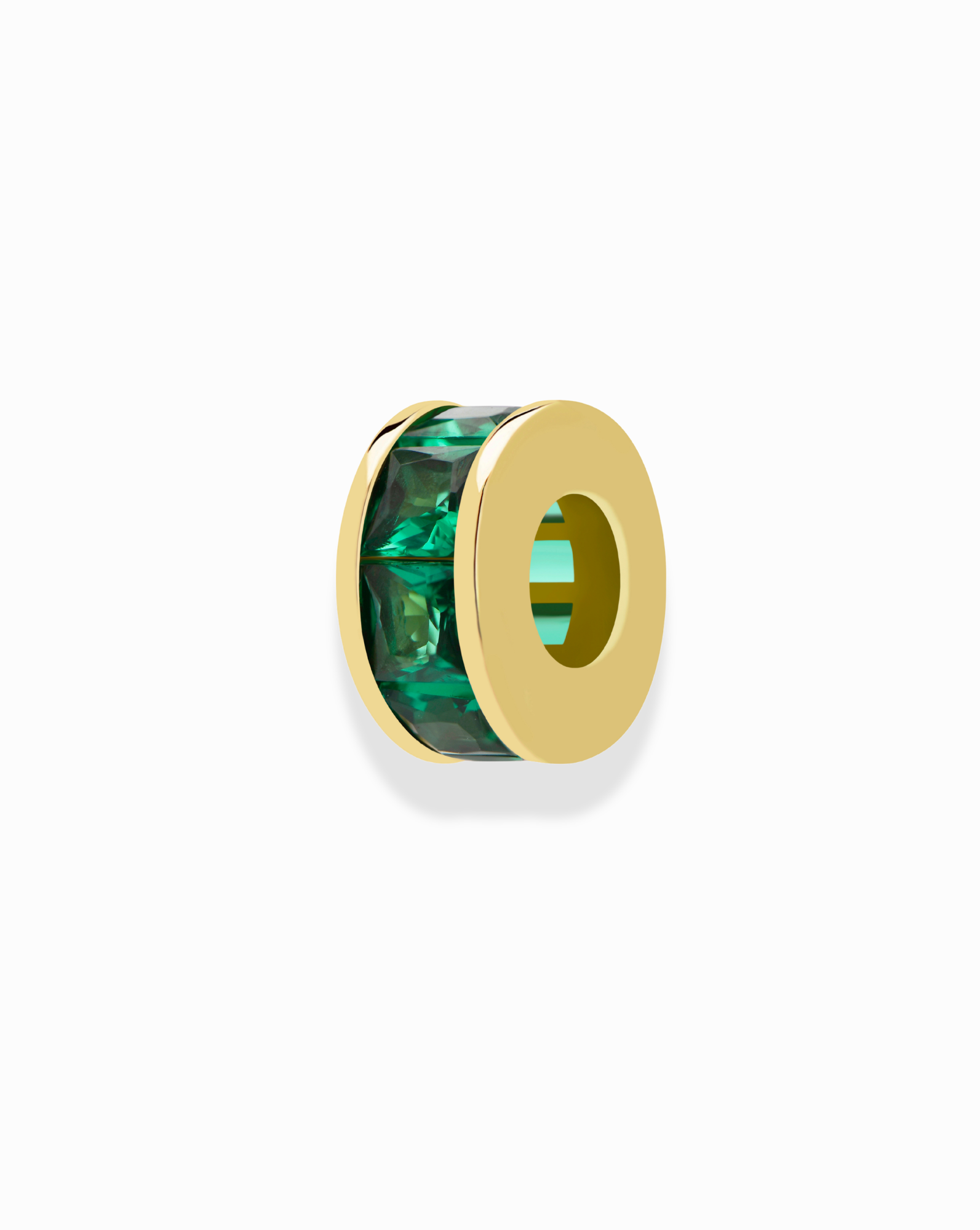 The Mod + Jo Este Birthstone Charm Spacer is a gold circular charm with a hollow center, accented by rectangular green gemstones around its edge, shown on a plain white background.