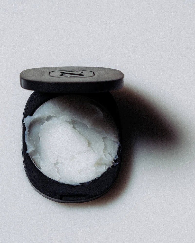 Black compact with white cream inside on a light gray background