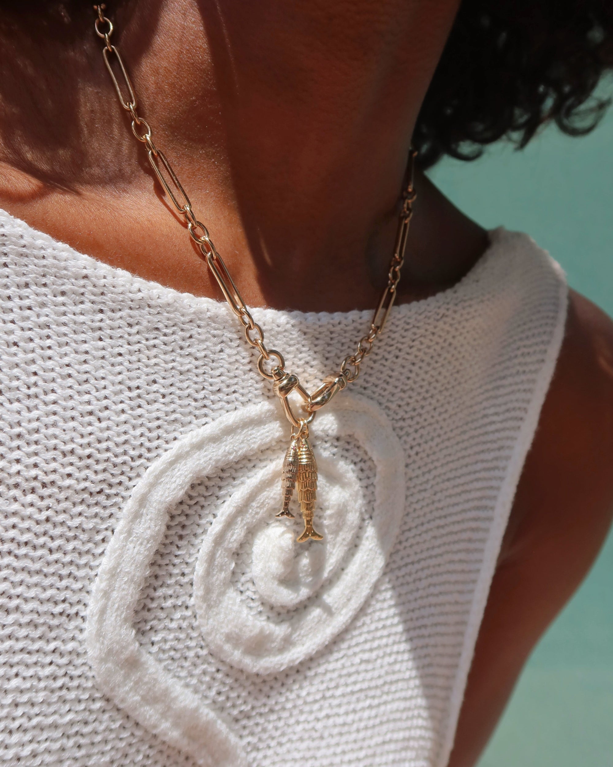 Person wearing a gold necklace with a pendant against a light blue background | Mod + Jo