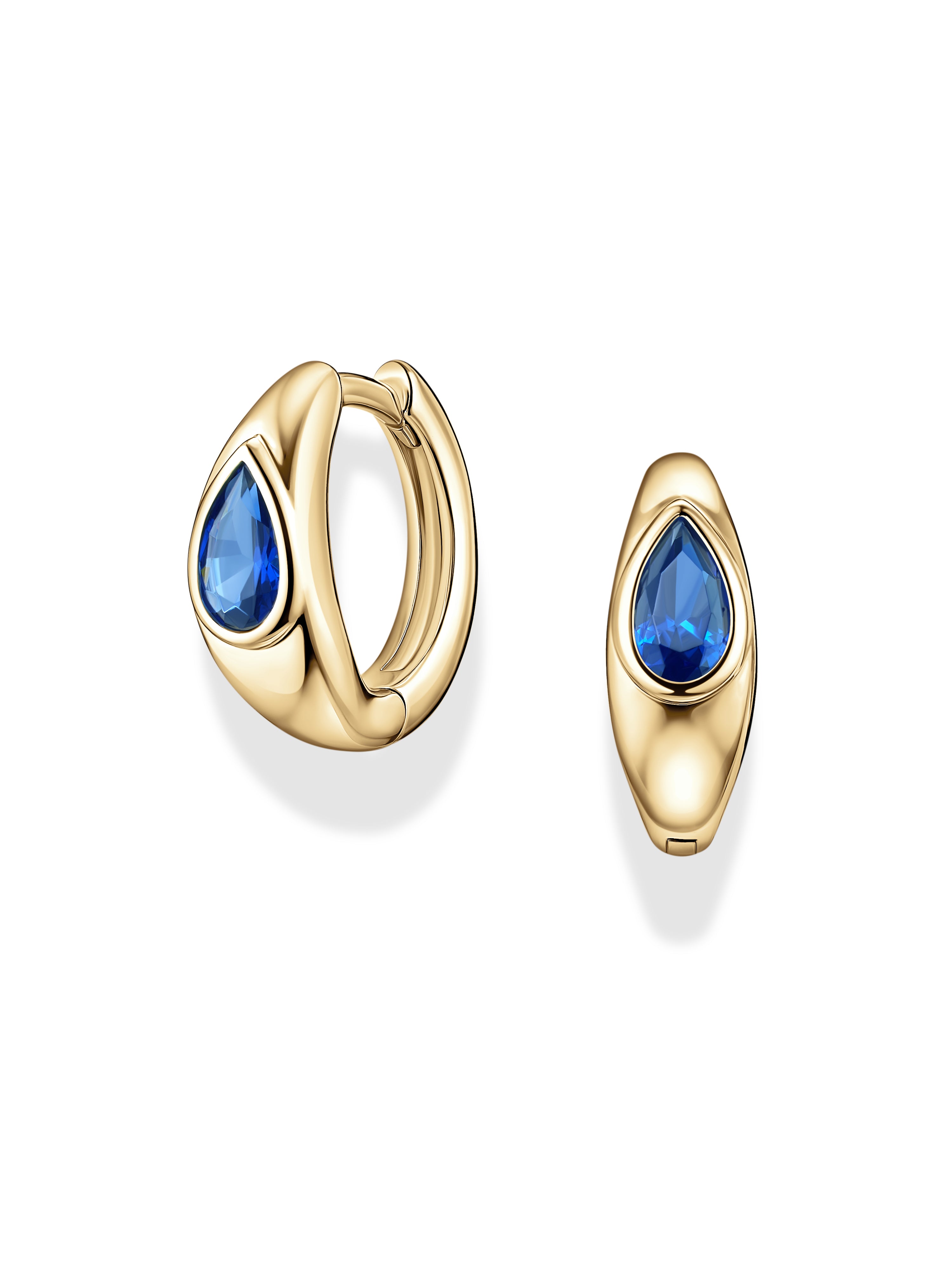 The Mod + Jo Tally Pear Huggie Hoops are gold-plated, nickel-free earrings featuring teardrop-shaped blue CZ gemstones set at the center. Shown against a white background, one earring is displayed from the front and the other from a side angle.