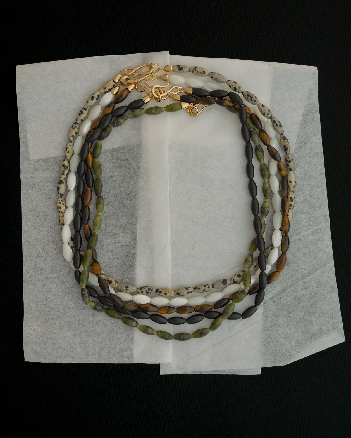 Sutton Gemstone Necklace featuring three 18″ layers of elongated, multi-colored mother of pearl rice-shaped stones with gold-toned clasps.