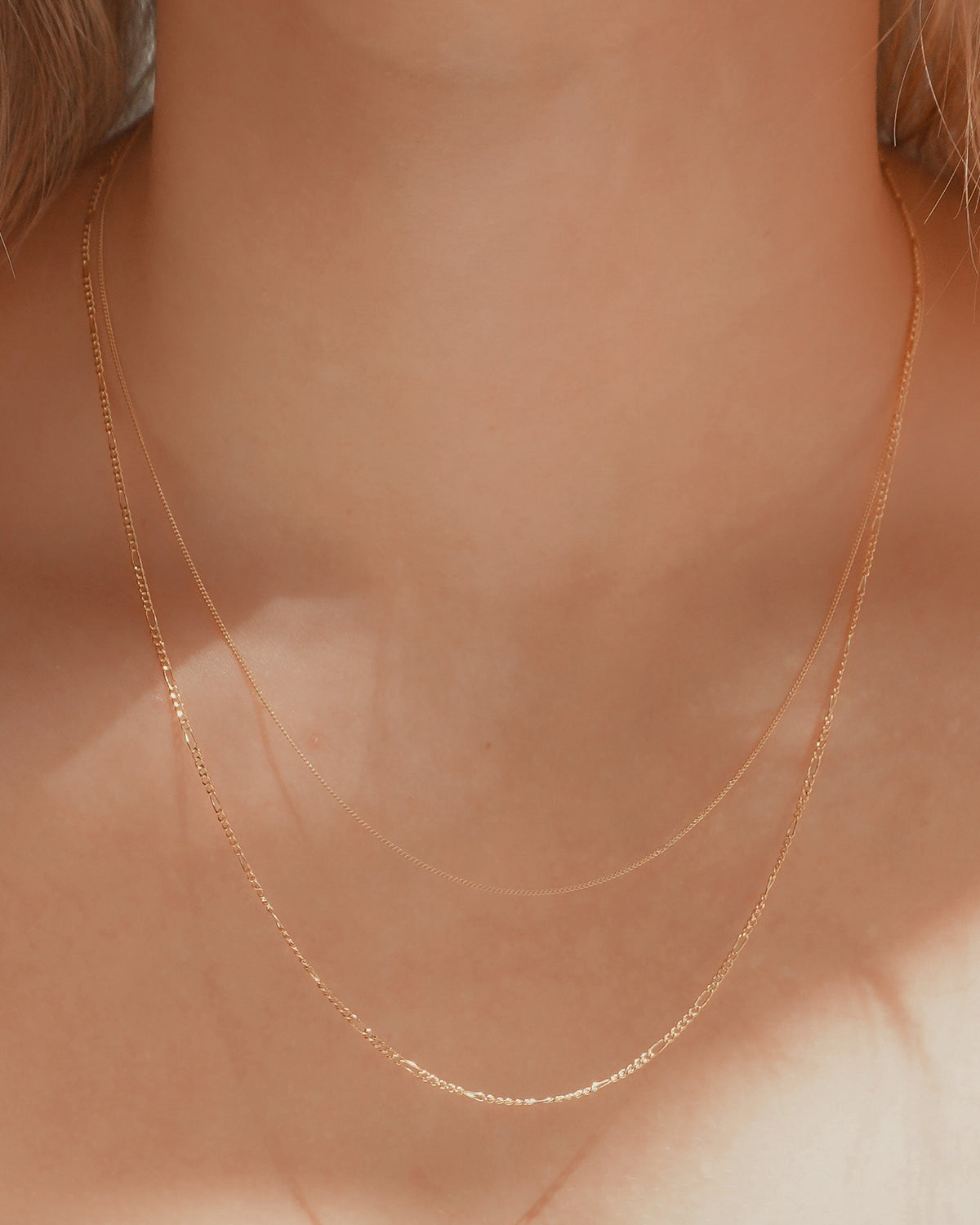 A person wearing the Lily + Gavin Set, consisting of a thin delicate gold chain and a slightly thicker gold curb chain.
