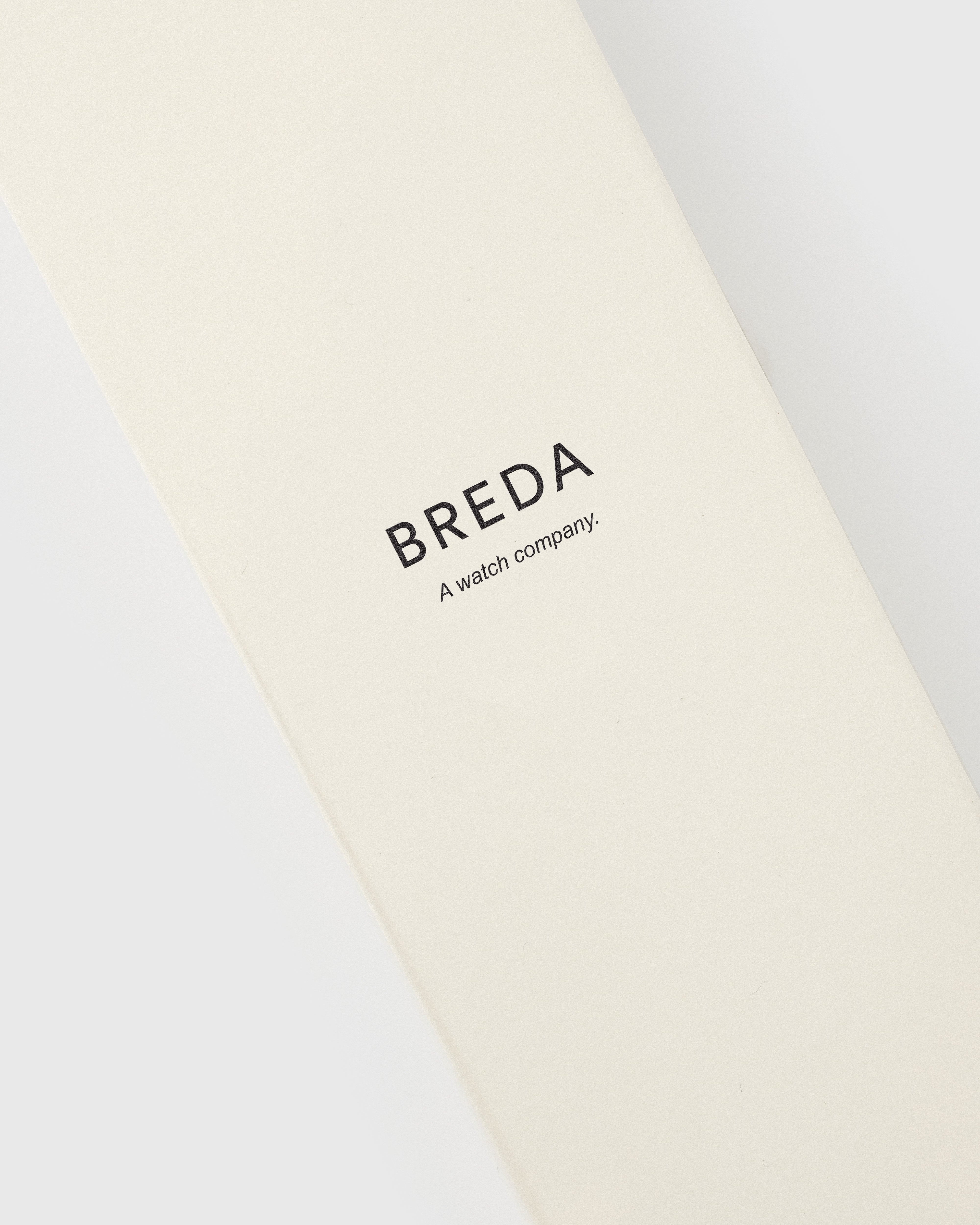 Beige strap with &#39;BREDA&#39; branding on a white background