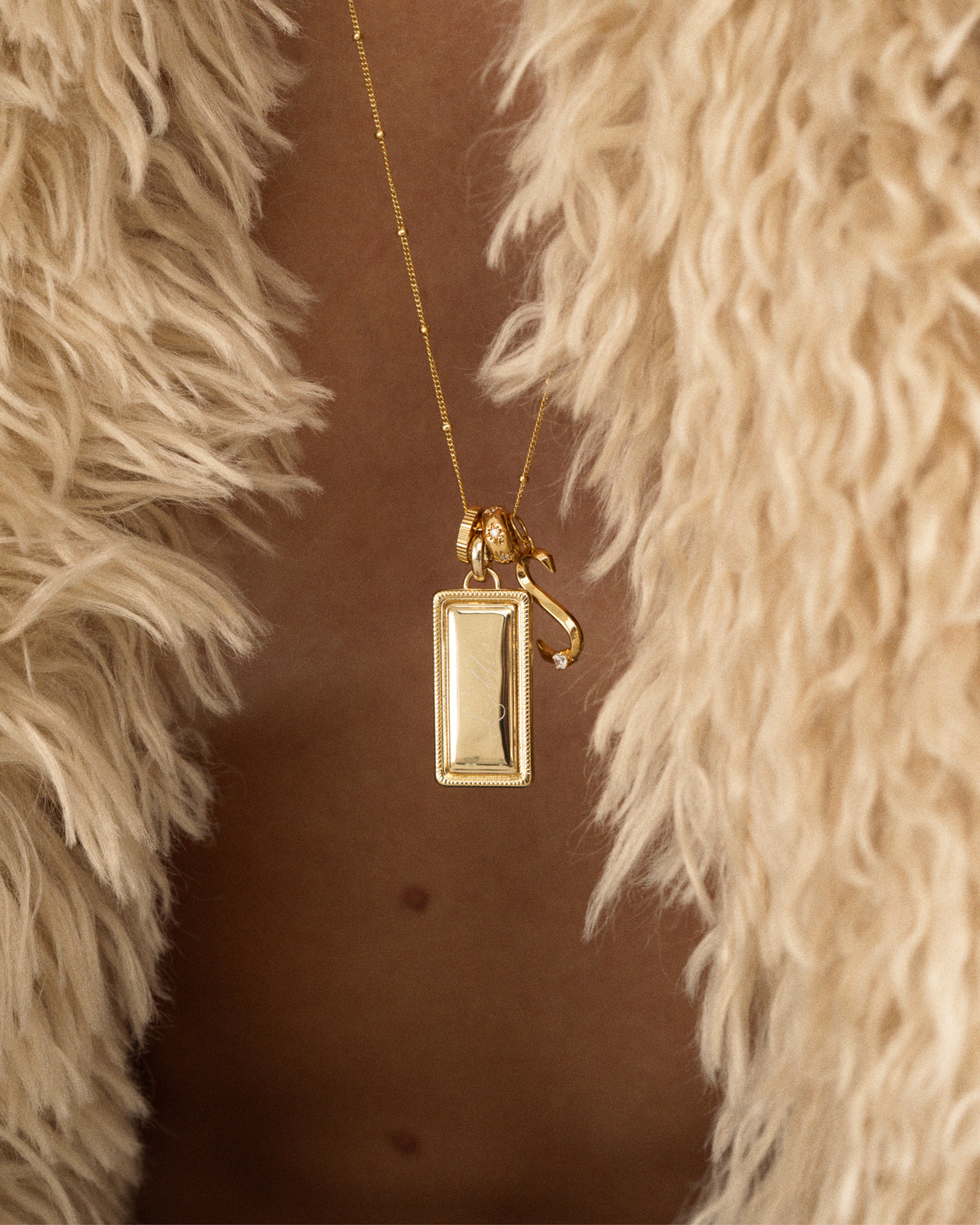Hattie Engravable Charm gold necklace featuring a rectangular engravable tablet pendant and a small script-style charm with a single stone.