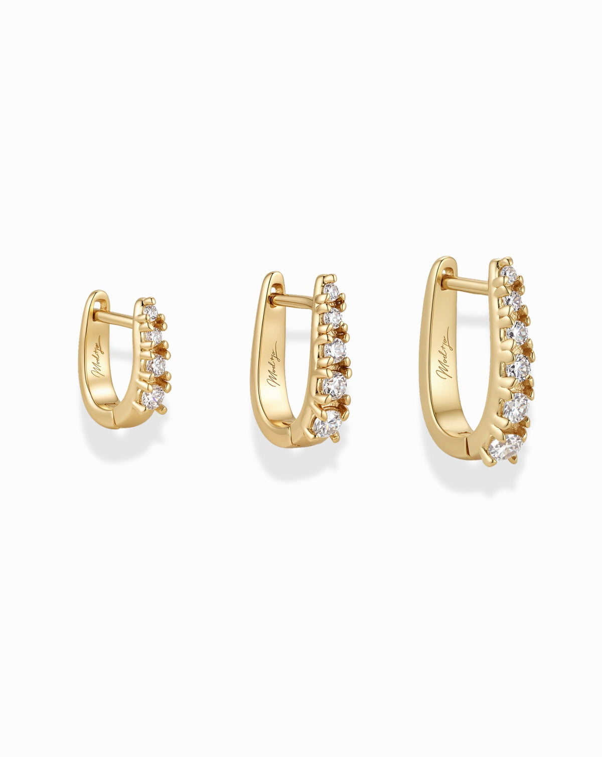 The Jules Huggies Gift Set features three gold huggie hoop earrings of increasing size, each with a row of five small clear stones.