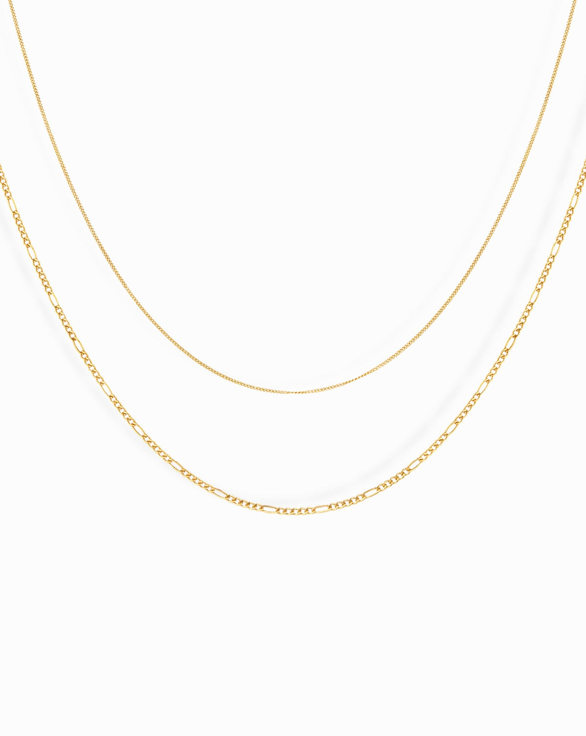 The Lily + Gavin Set by Mod + Jo features two gold-toned layered necklaces, one with a delicate curb chain and the other with a classic figaro link pattern.