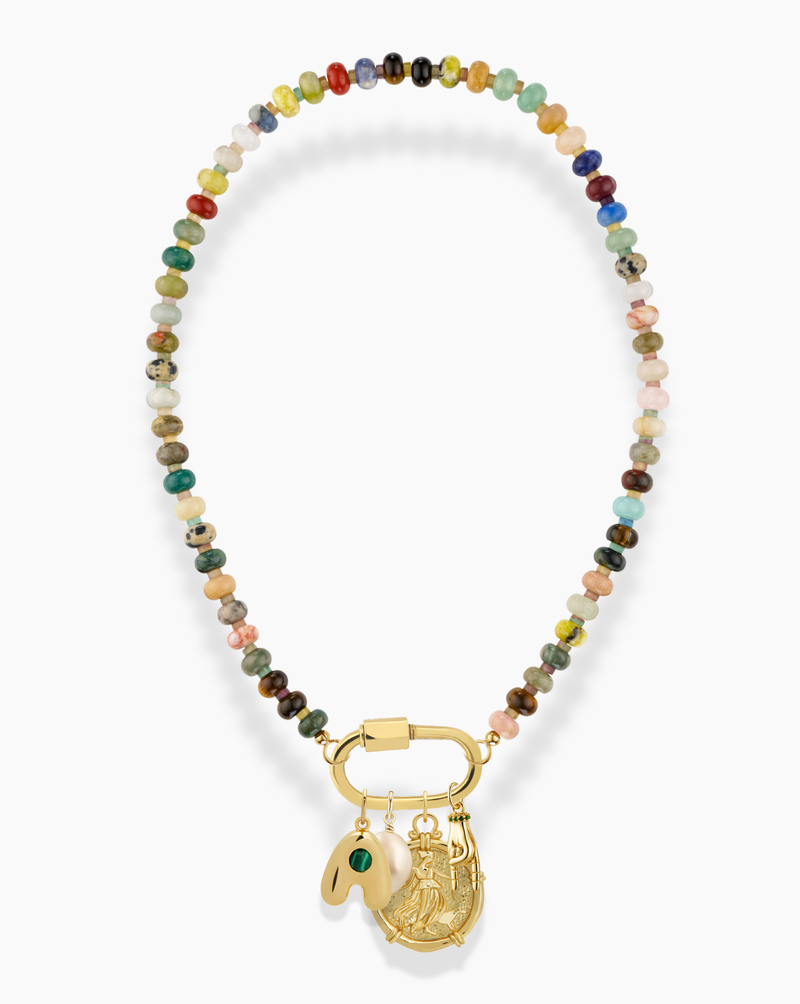 A colorful beaded necklace with a gold clasp, featuring three gold charms: a horseshoe, a jade pendant with a green stone, and a round engraved coin.