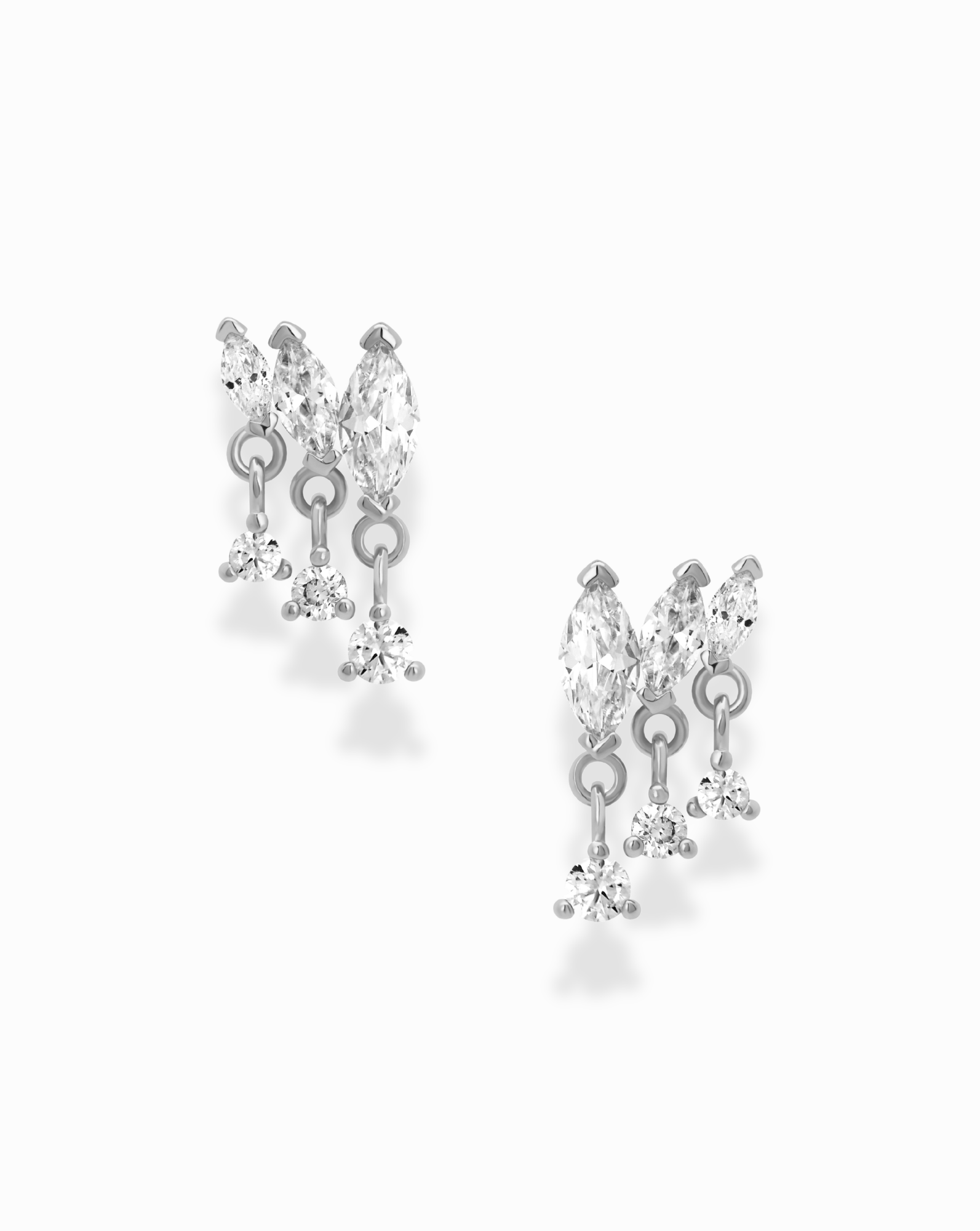 Introducing the Gabby Marquise Dangle Studs by Mod + Jo—a pair of silver earrings adorned with marquise-cut stones and dangling round crystals in a delicate, cascading design. These cubic zirconia earrings are elegantly showcased against a white background.
