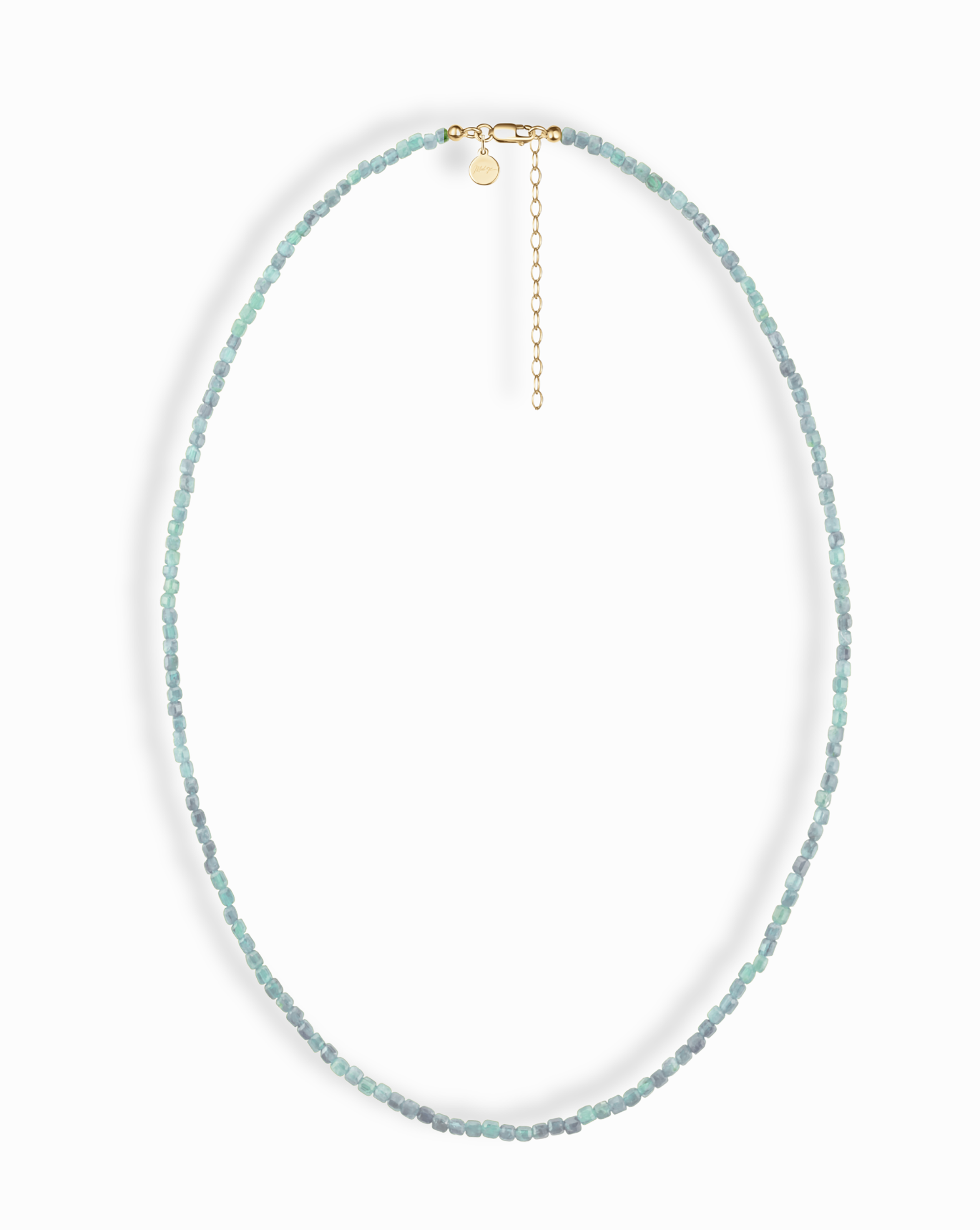 The Merit Gemstone Necklace by Mod + Jo showcases small, faceted aqua beads on a thin strand with a 14k gold-filled clasp, adjustable chain, and round gold charm. Necklace is photographed against a white background.