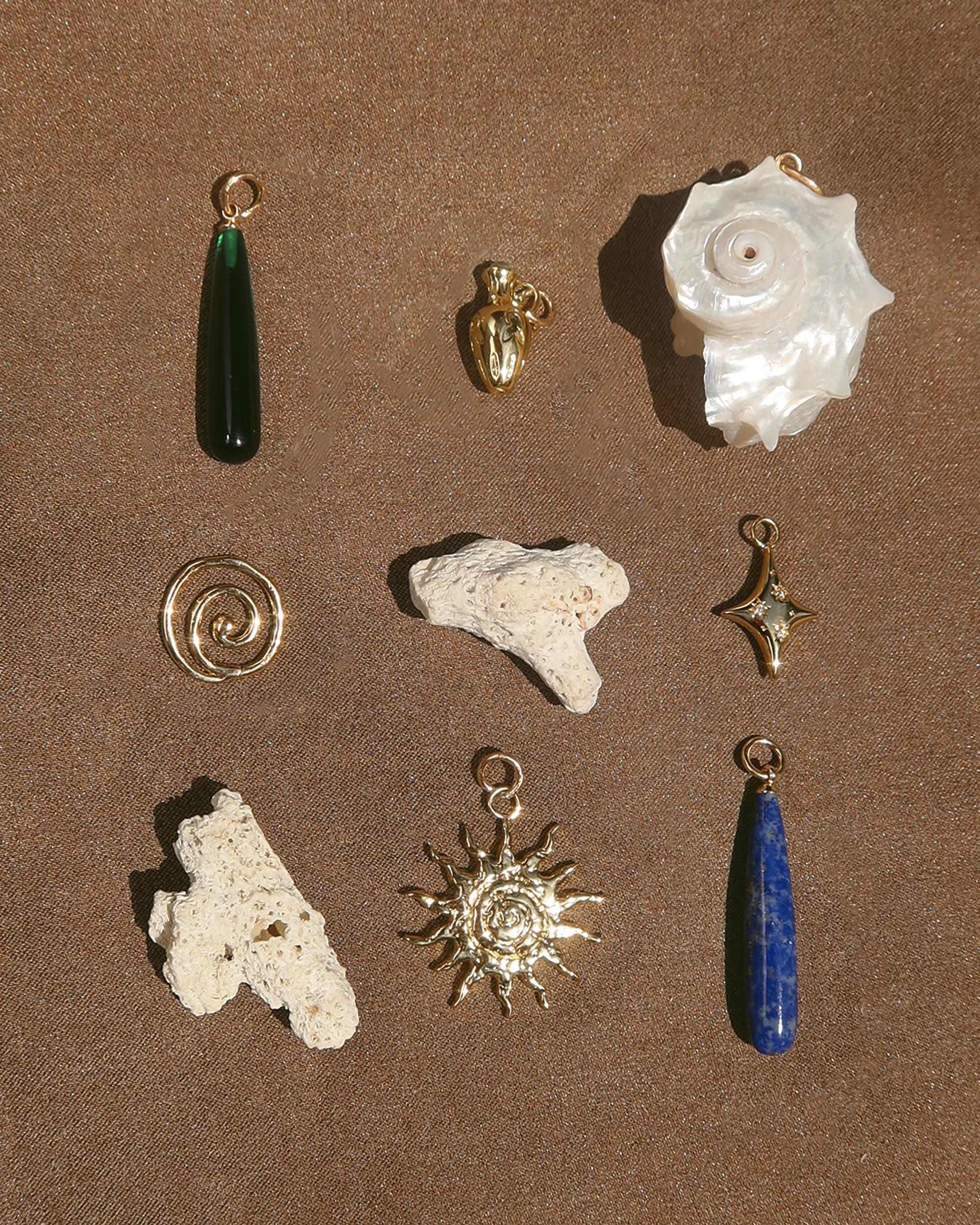 Collection of various jewelry pieces including pendants and stones on a brown surface | Mod + Jo