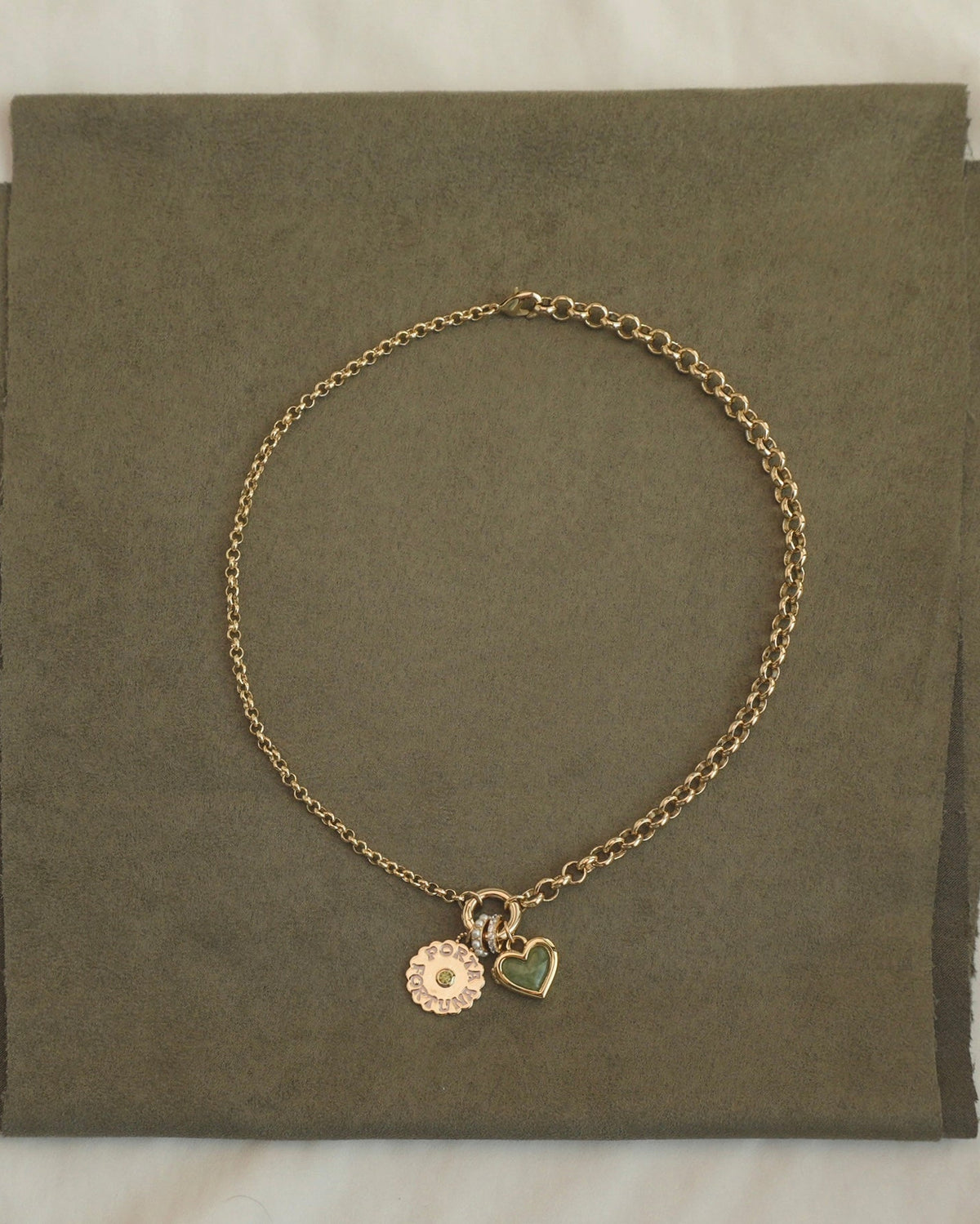 Mod + Jo Nessa Charm Clip Necklace featuring a 14k gold chain with a circular text-stamped charm, a small green heart, and a pave-set circle charm hanging from a central clip.
