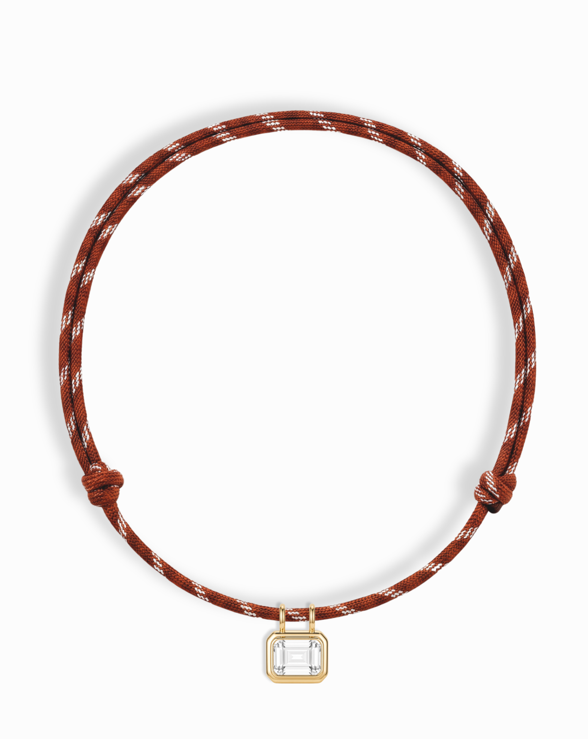 The Mod + Jo Tommy Sapphire Pendant Necklace is an adjustable brown and white paracord necklace featuring a gold and clear rectangular pendant at the center, displayed on a white background.