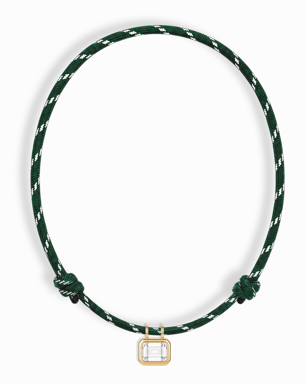 The Tommy Sapphire Pendant Necklace by Mod + Jo is a green and white braided, adjustable paracord necklace with knot details, highlighted by a rectangular lab-grown white sapphire pendant set in a central gold bezel.