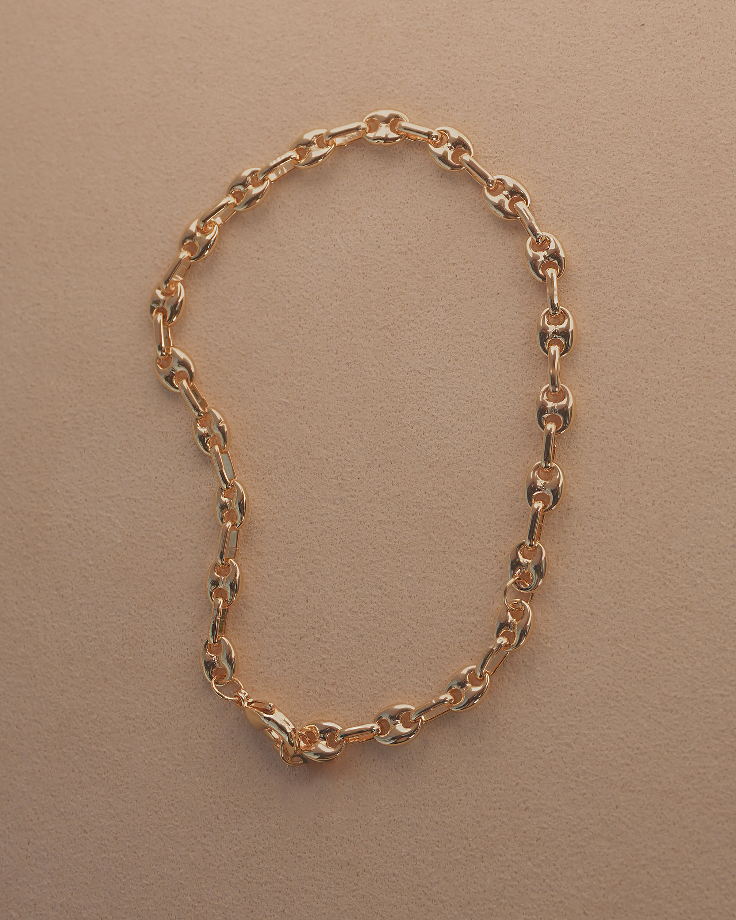 Gold chain bracelet on a beige background